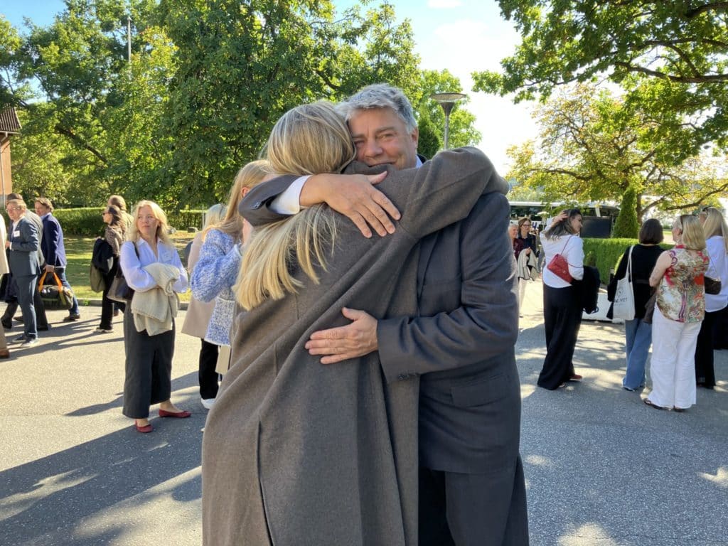 En före detta elev möter och omfamnar sin gamle lärare på skolgården i solsken, på Dekaden 2024. 